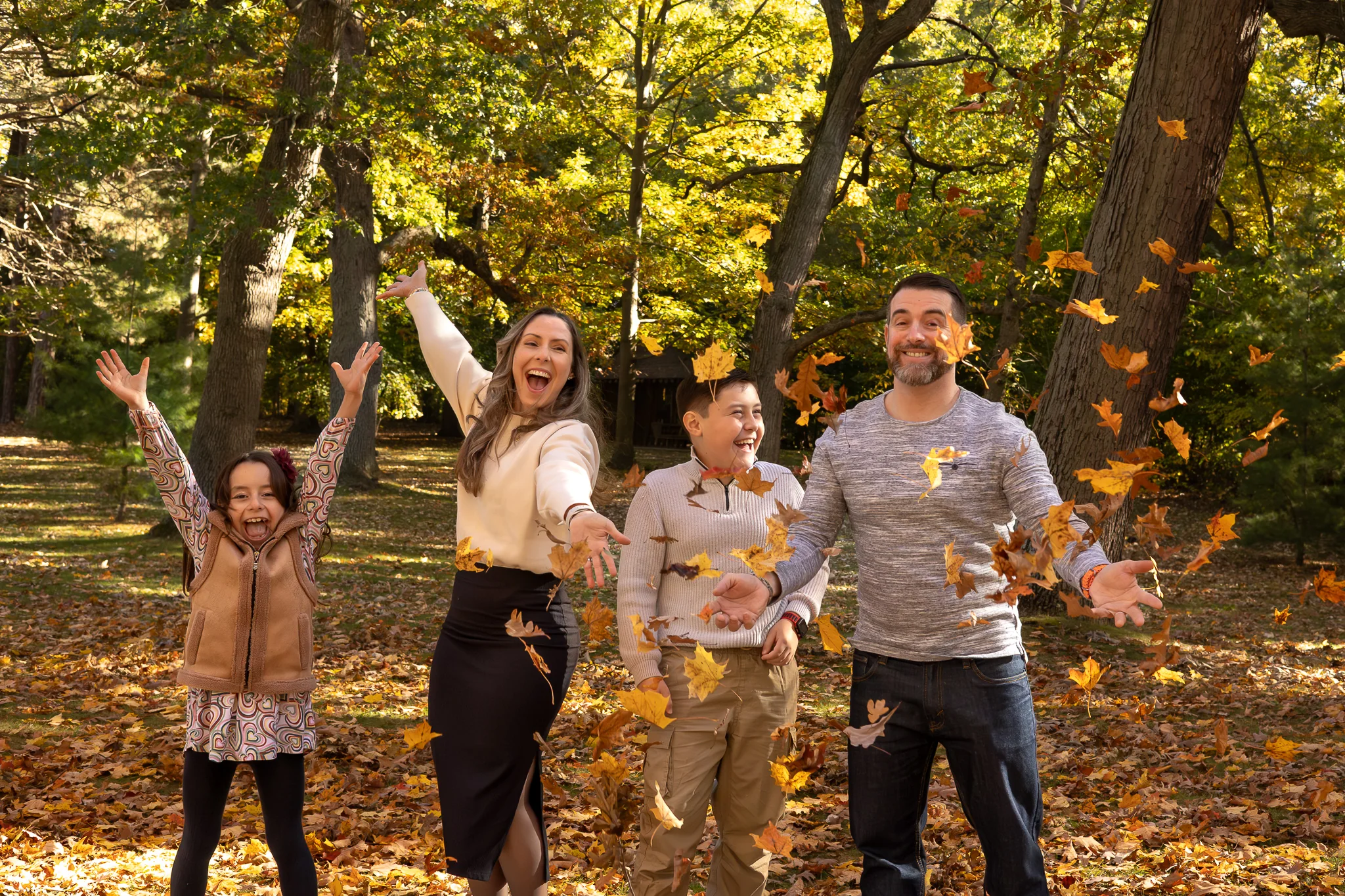Family laughing and tossing autumn leaves together