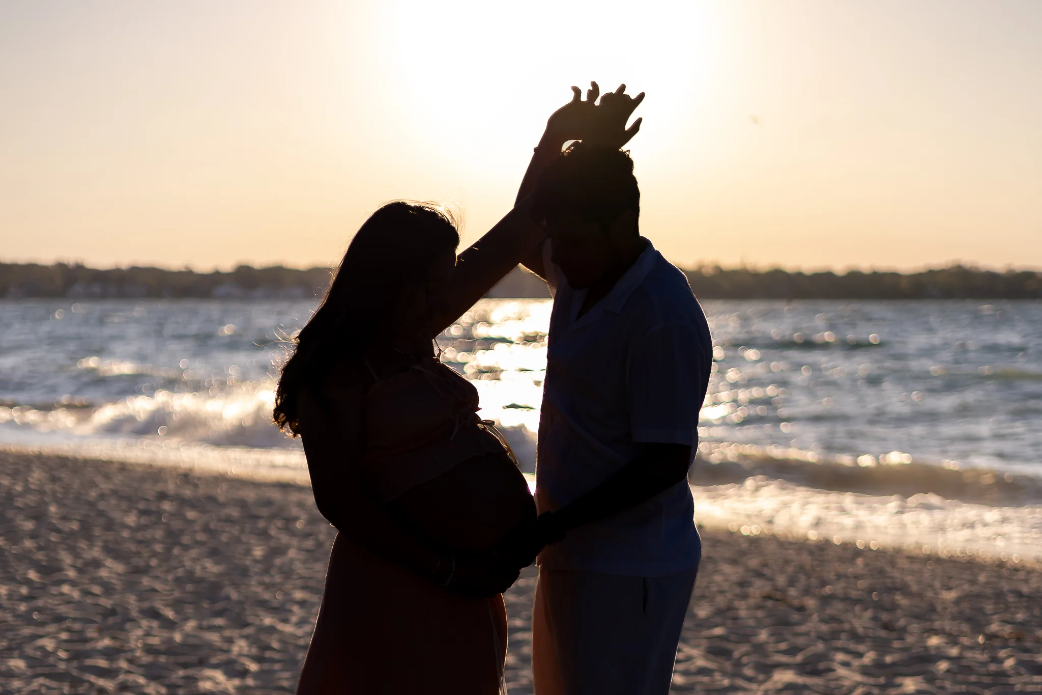 Expecting couple celebrating together at sunset