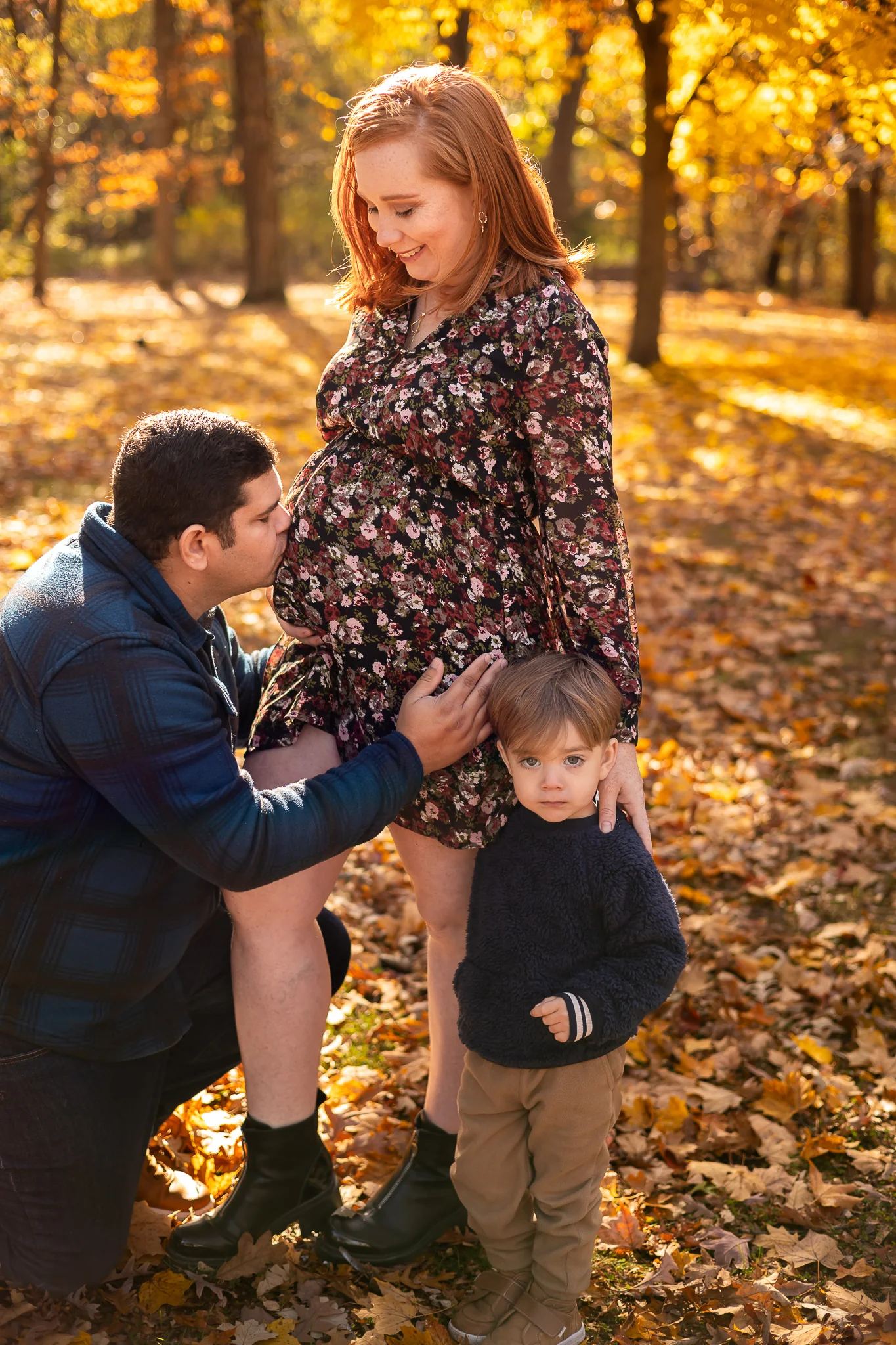 Family sharing an affectionate moment during an autumn maternity session